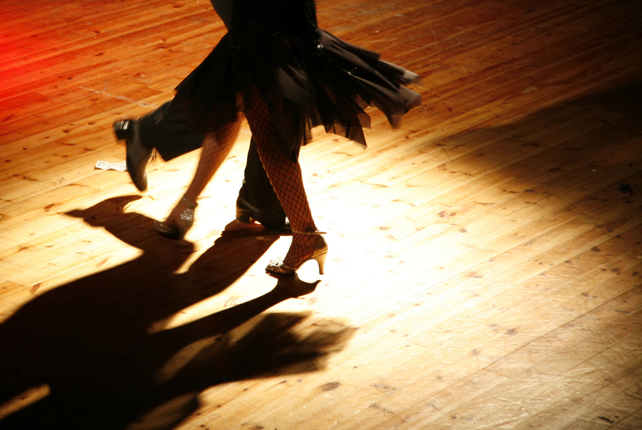 Twirling couple under the spotlights, in a colourful shot full of movement, taken during a latin dance night.